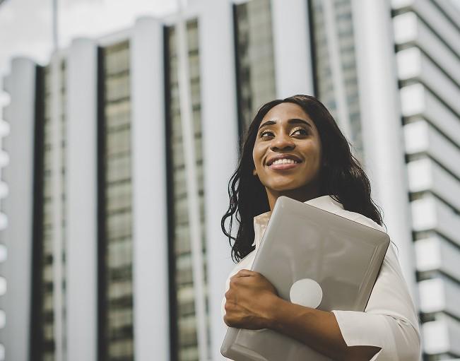 A smiling Kolomoni team member holding a laptop outside the office